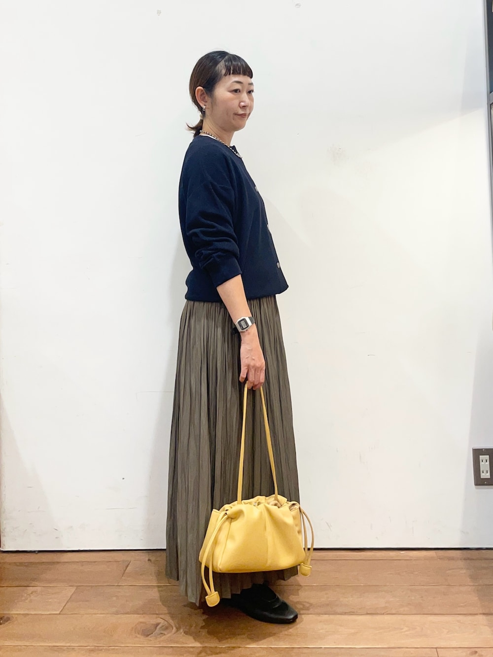 ブルー系のカーディガン/ボレロ、ベージュ系のスカート、イエロー系のショルダーバッグを着用したレディースの秋コーディネートの3枚目の写真