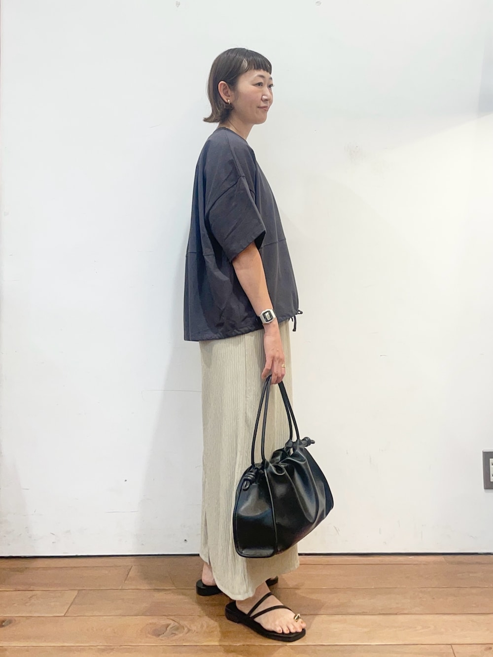 グレー系のTシャツ/カットソー、ベージュ系のスカート、ブラック系のトートバッグを着用したレディースの夏コーディネートの3枚目の写真