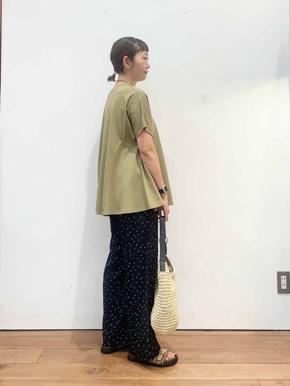 グリーン系のTシャツ/カットソー、ベージュ系のトートバッグ、ベージュ系のサンダルを着用したレディースの夏コーディネートの3枚目の写真