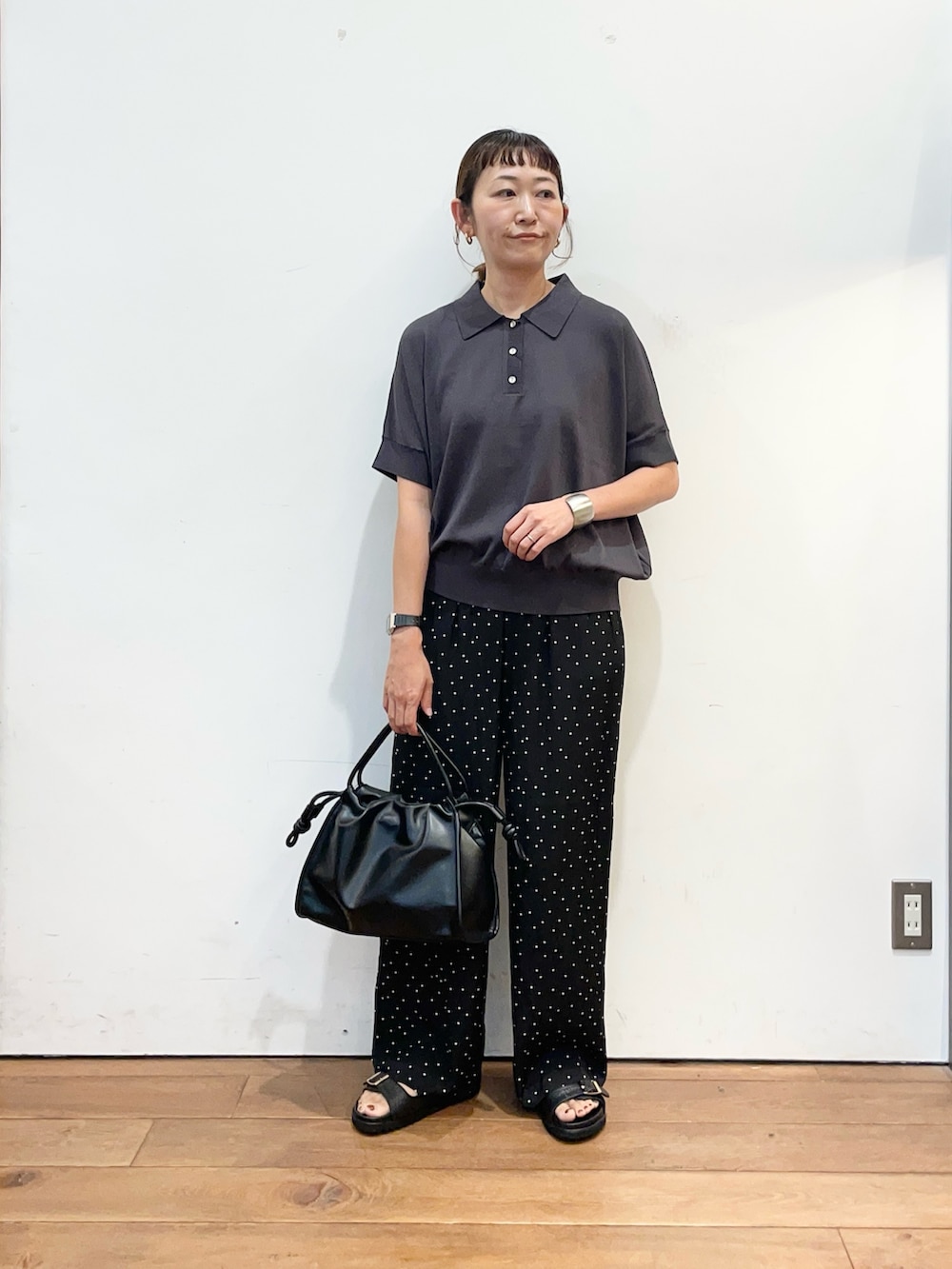 グレー系のニット/セーター、ブラック系のトートバッグ、ブラック系のサンダルを着用したレディースの夏コーディネートの2枚目の写真