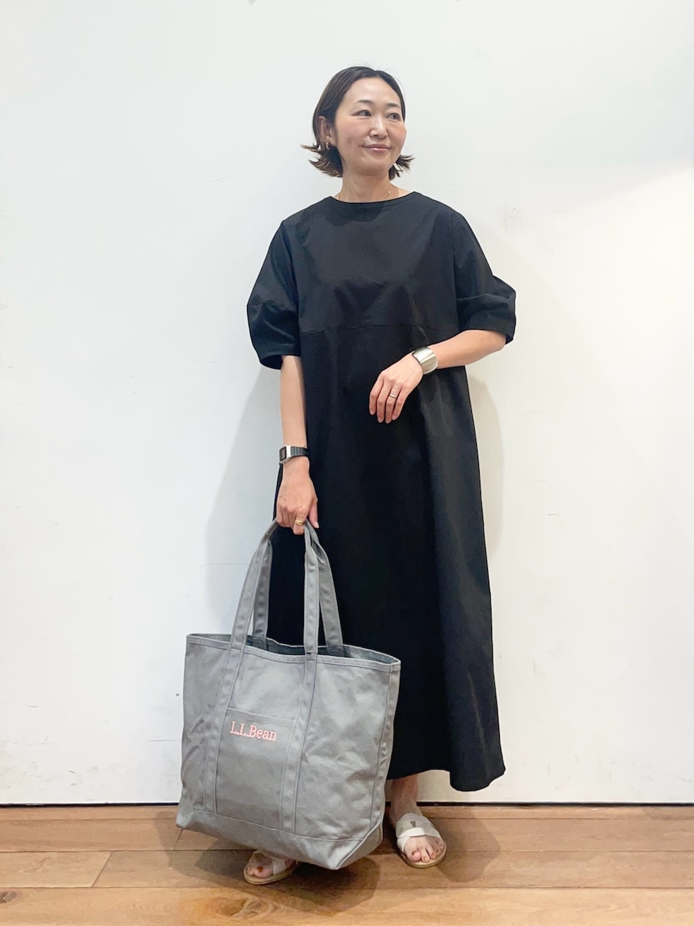 ブラック系のワンピース、ホワイト系のサンダル、グレー系のトートバッグを着用したレディースの春コーディネートの3枚目の写真