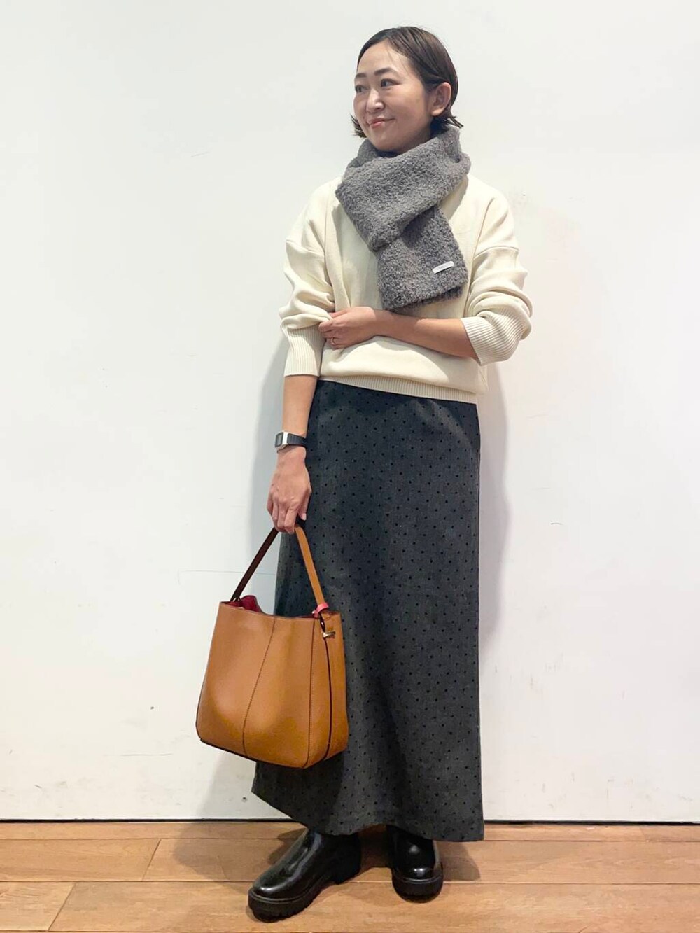 ブラウン系のハンドバッグ、ブラック系のブーツ、ホワイト系のニット/セーターを着用したレディースの秋コーディネートの2枚目の写真