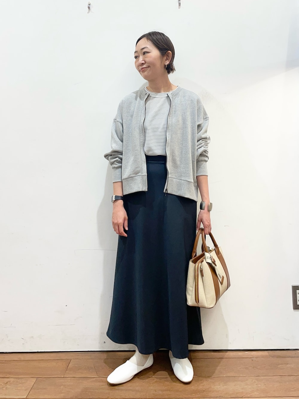 ブルー系のスカート、ホワイト系のその他シューズ、ホワイト系のハンドバッグを着用したレディースの春コーディネートの2枚目の写真