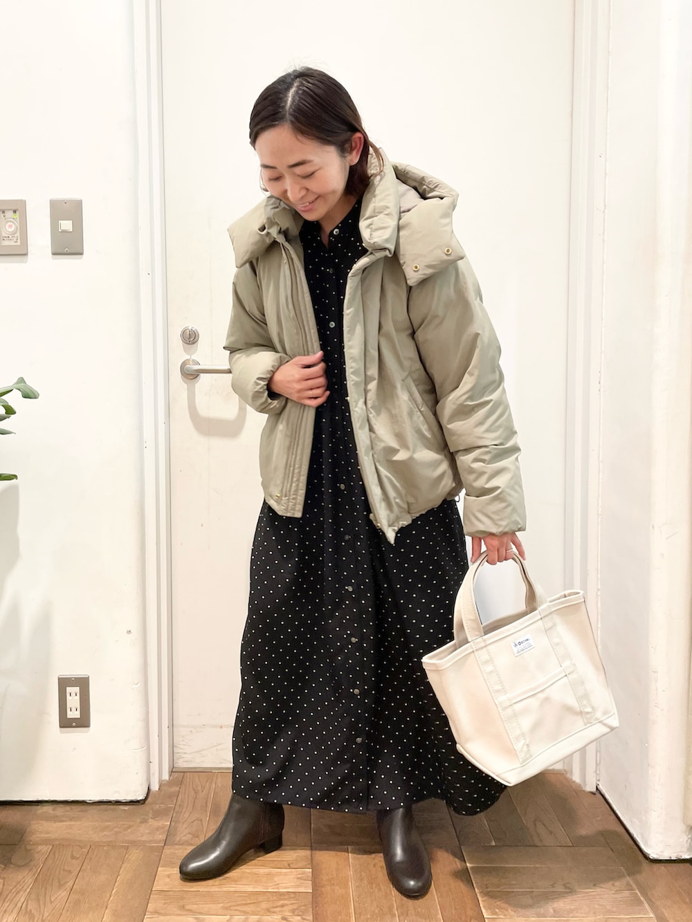 グレー系のダウンジャケット/コート、ブラック系のワンピース、ブラウン系のブーツを着用したレディースの冬コーディネートの2枚目の写真