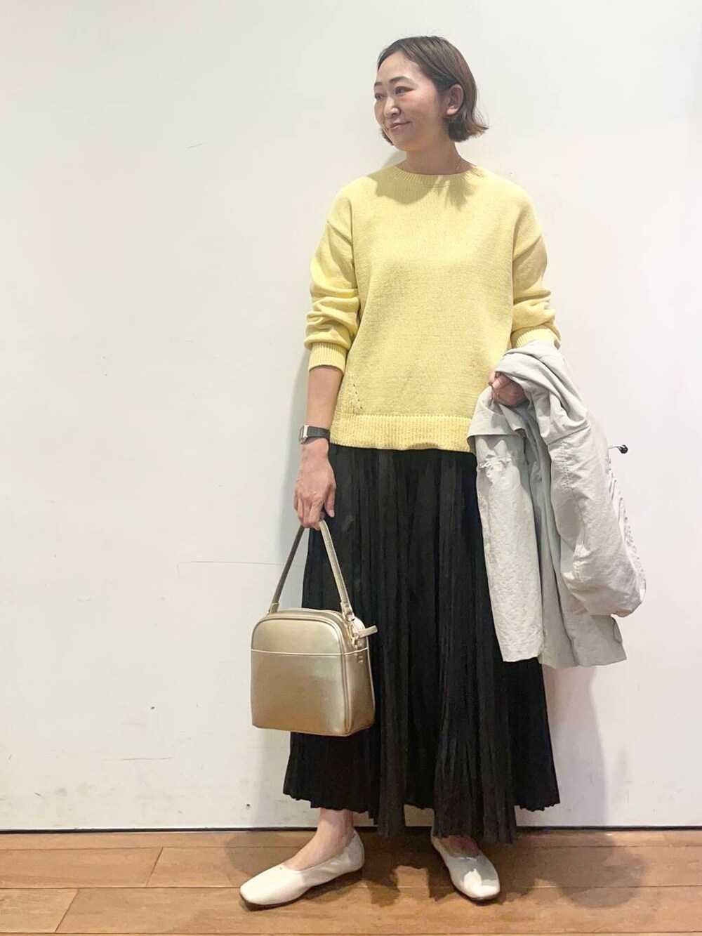 ゴールド系のショルダーバッグ、ブラック系のスカート、ホワイト系のバレエシューズを着用したレディースの春コーディネートの6枚目の写真
