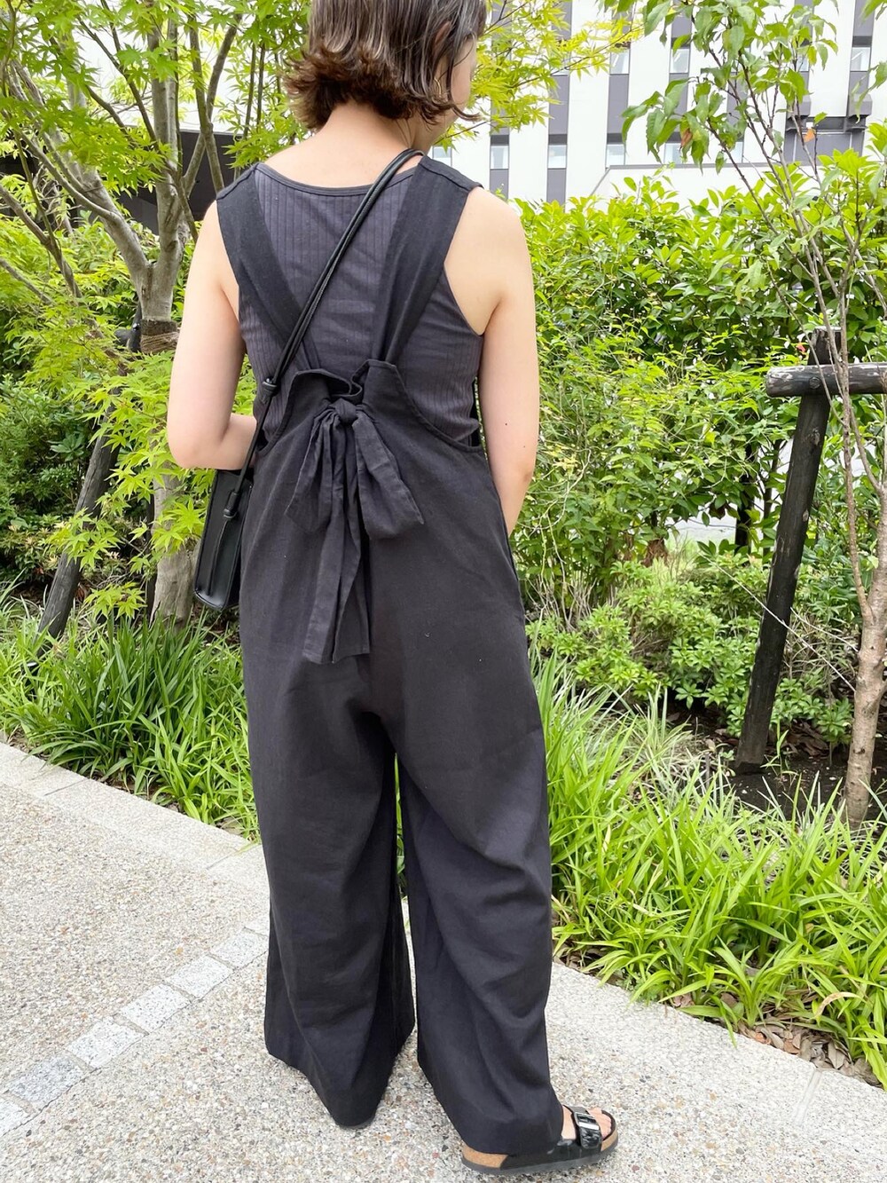 ブラック系のサロペット/オーバーオール、ブラック系のショルダーバッグ、ブラック系のサンダルを着用したレディースの夏コーディネートの4枚目の写真
