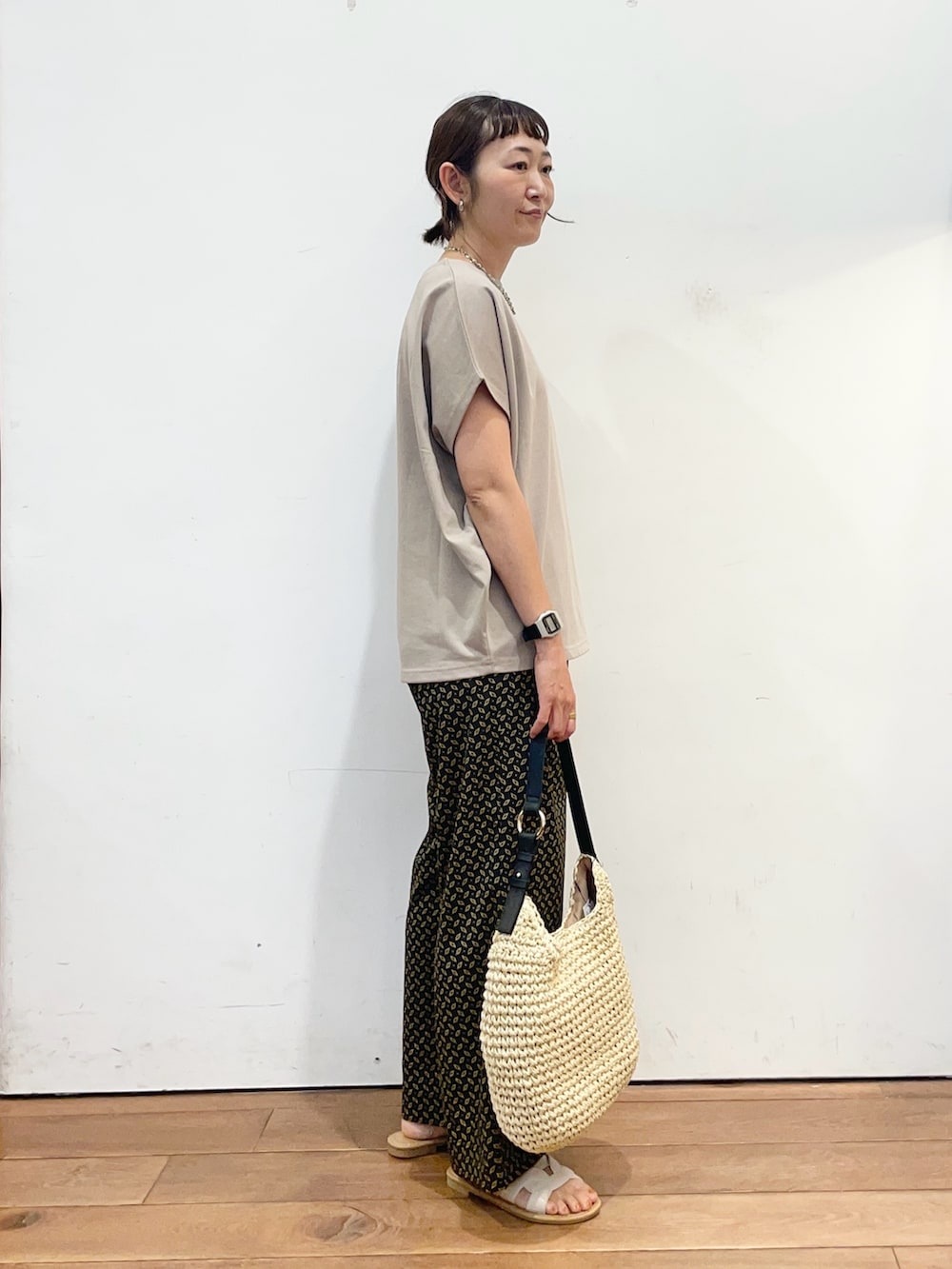 ベージュ系のトートバッグ、ホワイト系のサンダル、グレー系のTシャツ/カットソーを着用したレディースの夏コーディネートの3枚目の写真