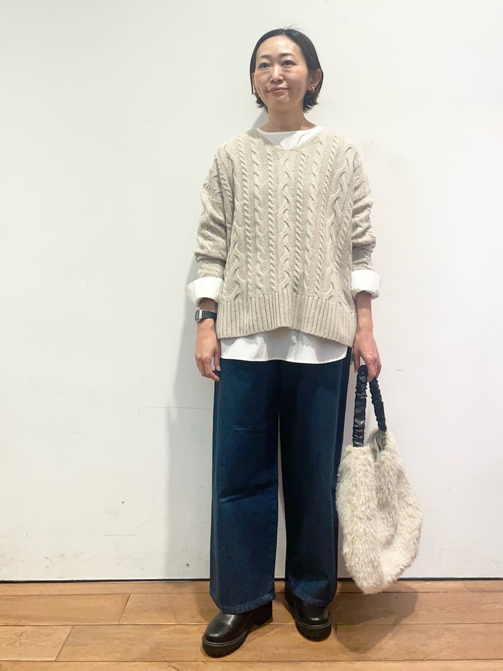 ベージュ系のニット/セーター、ホワイト系のシャツ/ブラウス、ブルー系のデニムパンツを着用したレディースの冬コーディネートの3枚目の写真