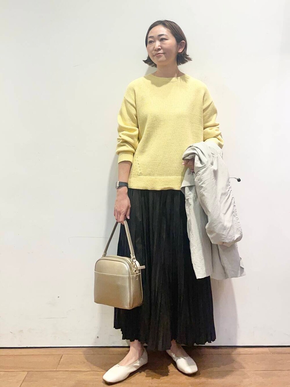 ゴールド系のショルダーバッグ、ブラック系のスカート、ホワイト系のバレエシューズを着用したレディースの春コーディネートの5枚目の写真