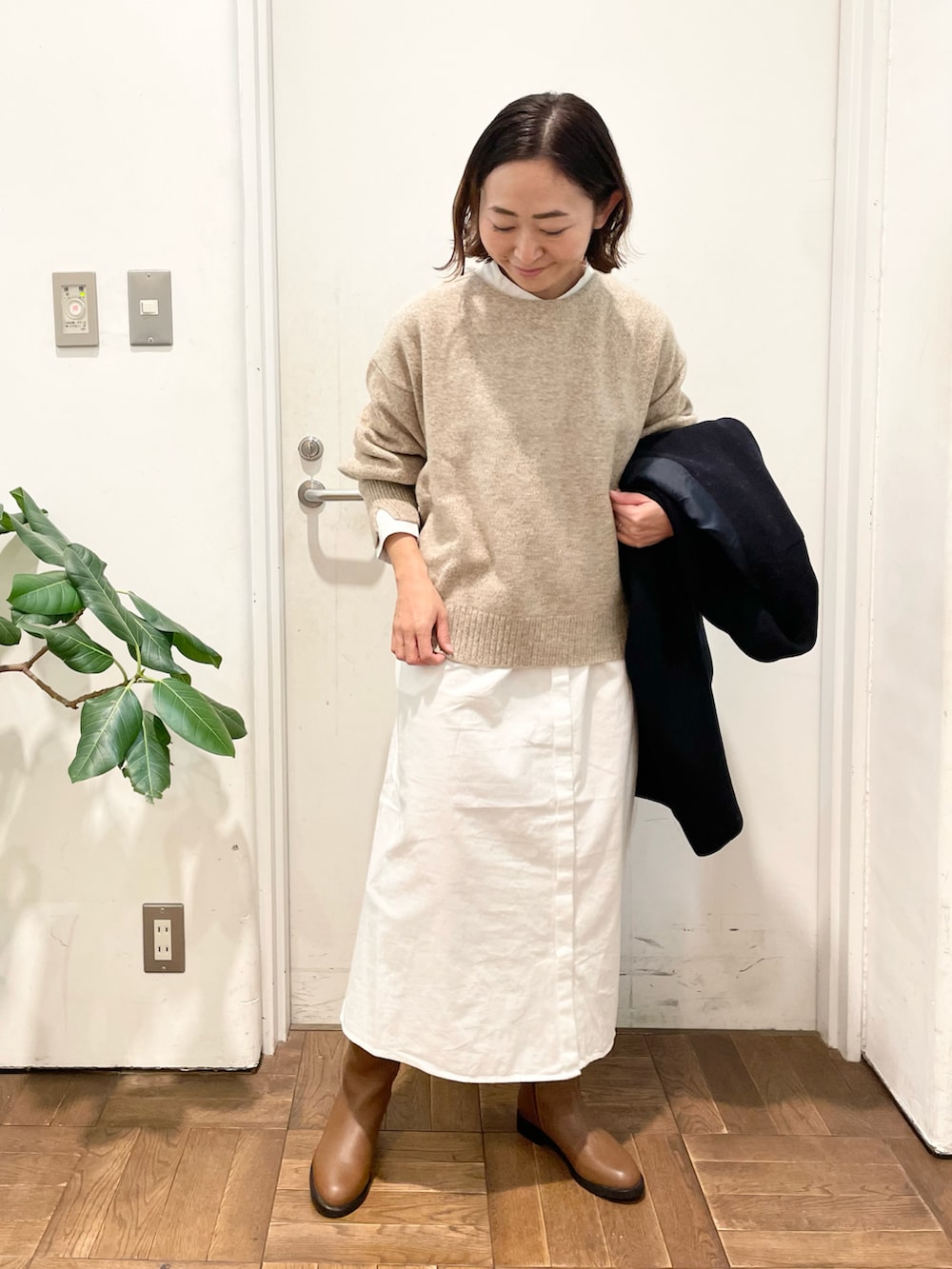 ベージュ系のニット/セーター、ホワイト系のワンピース、ブラウン系のブーツを着用したレディースの冬コーディネートの3枚目の写真