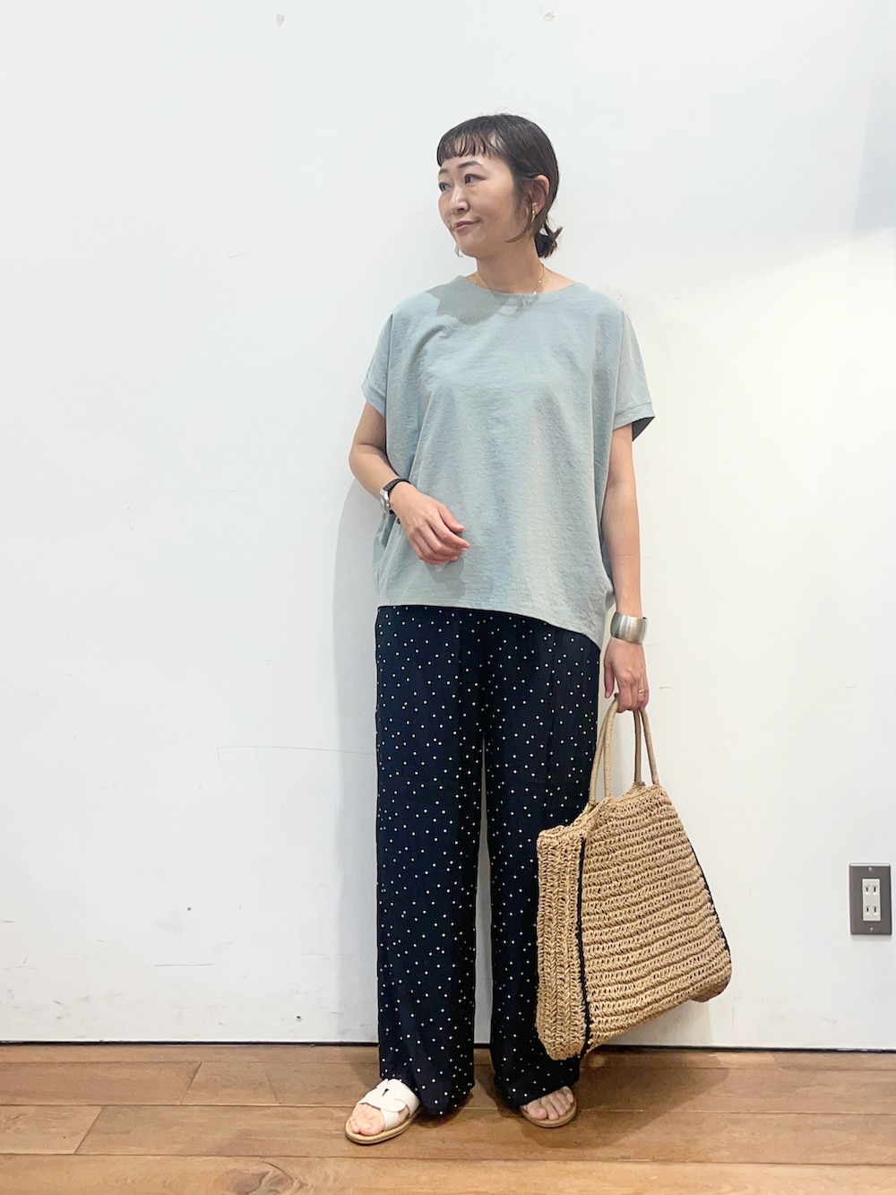 グリーン系のTシャツ/カットソー、ベージュ系のトートバッグ、ホワイト系のサンダルを着用したレディースの夏コーディネートの2枚目の写真