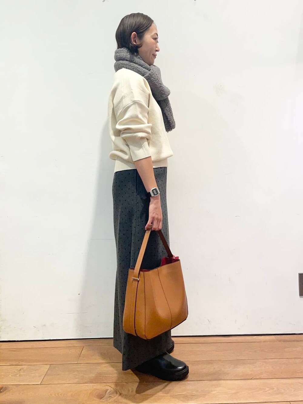 ブラウン系のハンドバッグ、ブラック系のブーツ、ホワイト系のニット/セーターを着用したレディースの秋コーディネートの4枚目の写真