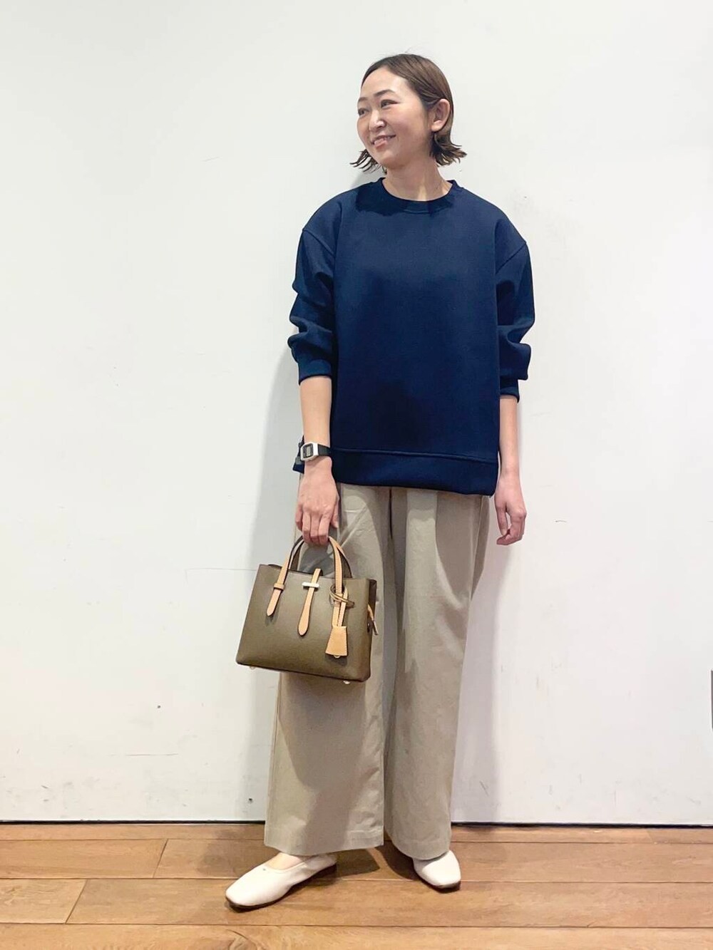 ブラウン系のハンドバッグ、ブルー系のその他トップス、ホワイト系のバレエシューズを着用したレディースの春コーディネートの2枚目の写真