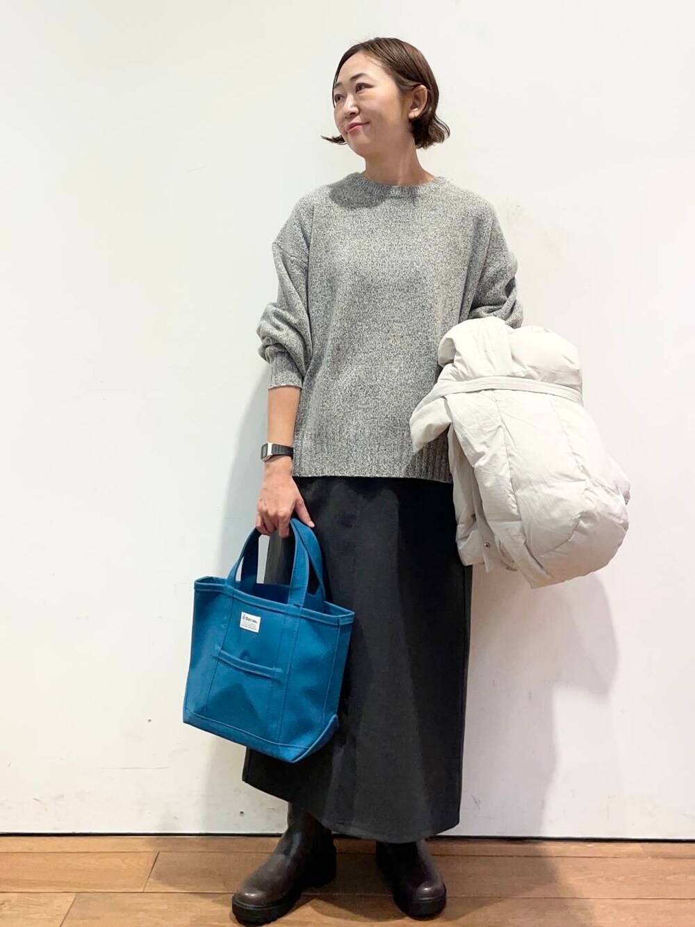 ホワイト系のダウンジャケット/コート、グレー系のニット/セーター、ブラウン系のブーツを着用したレディースの冬コーディネートの5枚目の写真