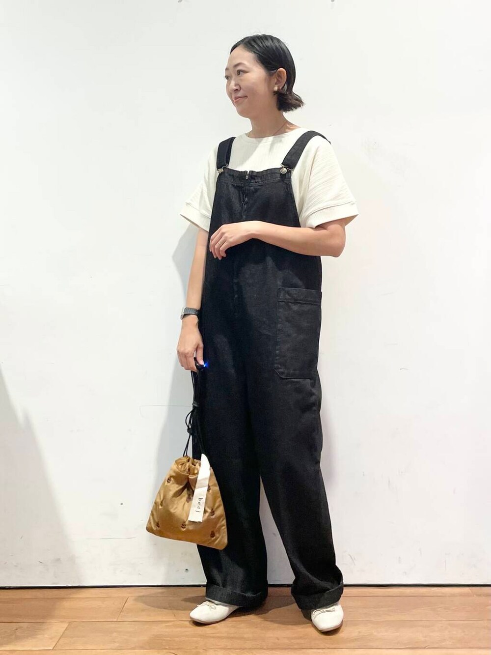 ホワイト系のTシャツ/カットソー、ブラウン系のバレエシューズ、ブラック系のサロペット/オーバーオールを着用したレディースの秋コーディネートの2枚目の写真