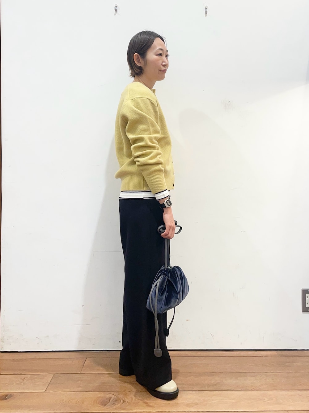 イエロー系のカーディガン/ボレロ、ホワイト系のTシャツ/カットソー、ブルー系のショルダーバッグを着用したレディースの冬コーディネートの4枚目の写真