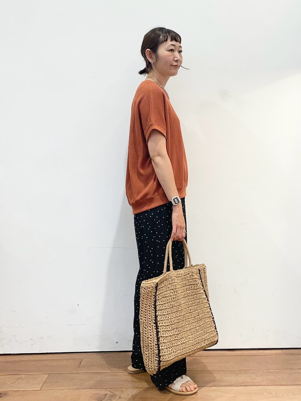 オレンジ系のTシャツ/カットソー、ブラック系のその他パンツ、ベージュ系のトートバッグを着用したレディースの夏コーディネートの3枚目の写真