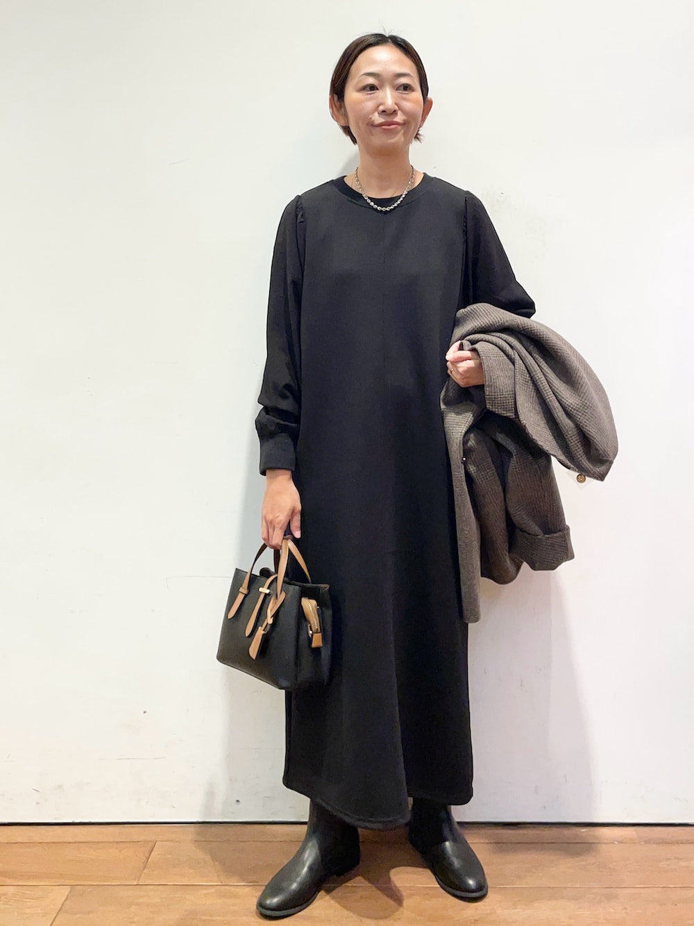 ブラック系のブーツ、ブラック系のハンドバッグ、その他のその他アウターを着用したレディースの秋コーディネートの6枚目の写真