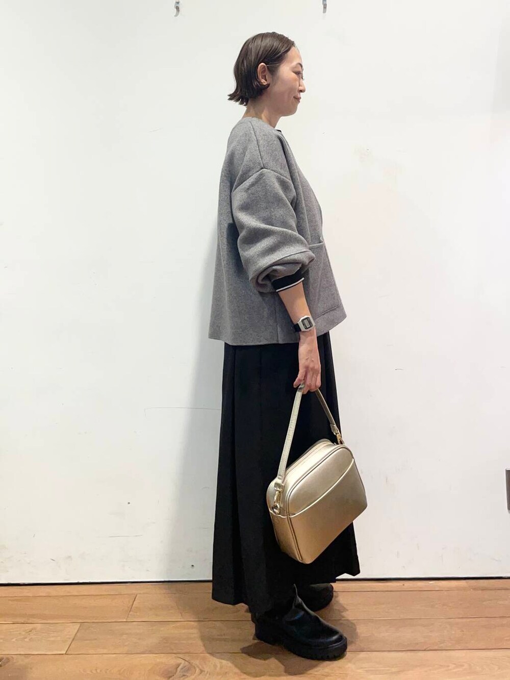 ブラック系のTシャツ/カットソー、ゴールド系のショルダーバッグ、ブラック系のブーツを着用したレディースの秋コーディネートの4枚目の写真