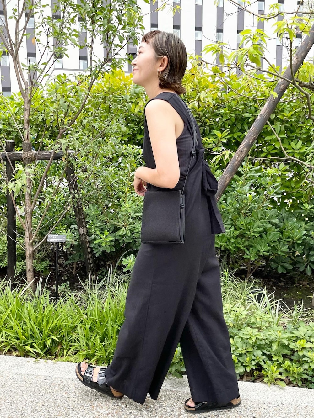 ブラック系のサロペット/オーバーオール、ブラック系のショルダーバッグ、ブラック系のサンダルを着用したレディースの夏コーディネートの3枚目の写真