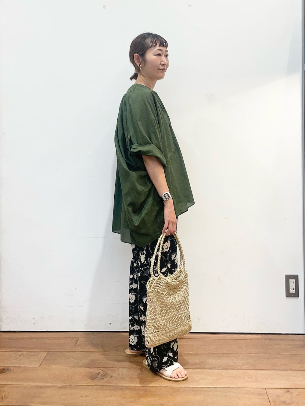 グリーン系のシャツ/ブラウス、ゴールド系のトートバッグ、ホワイト系のサンダルを着用したレディースの夏コーディネートの3枚目の写真