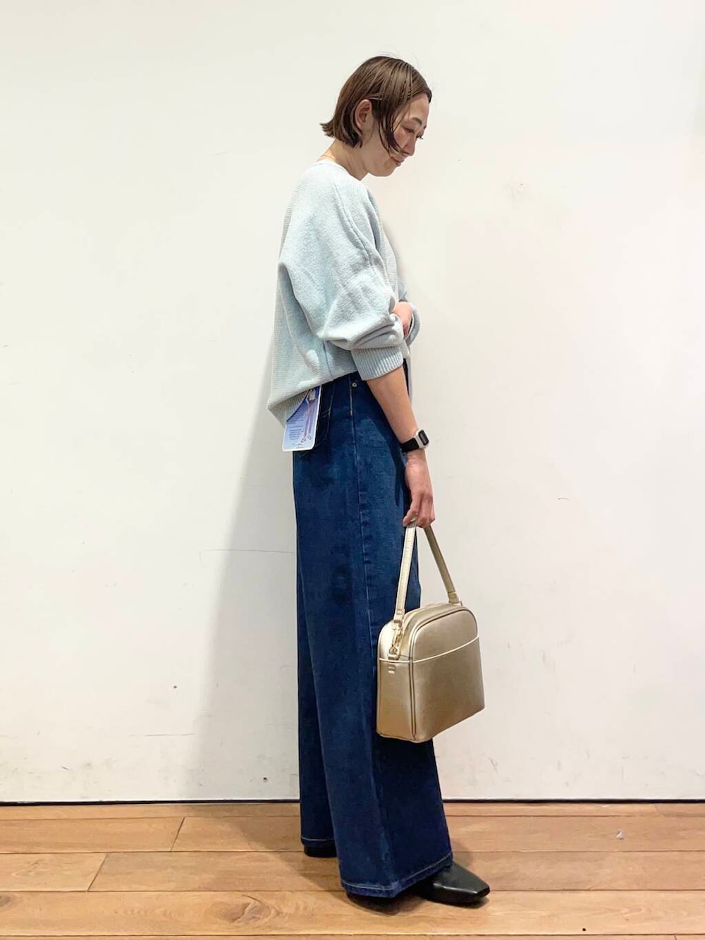 ゴールド系のショルダーバッグ、ブラック系のバレエシューズ、ブルー系のデニムパンツを着用したレディースの冬コーディネートの4枚目の写真