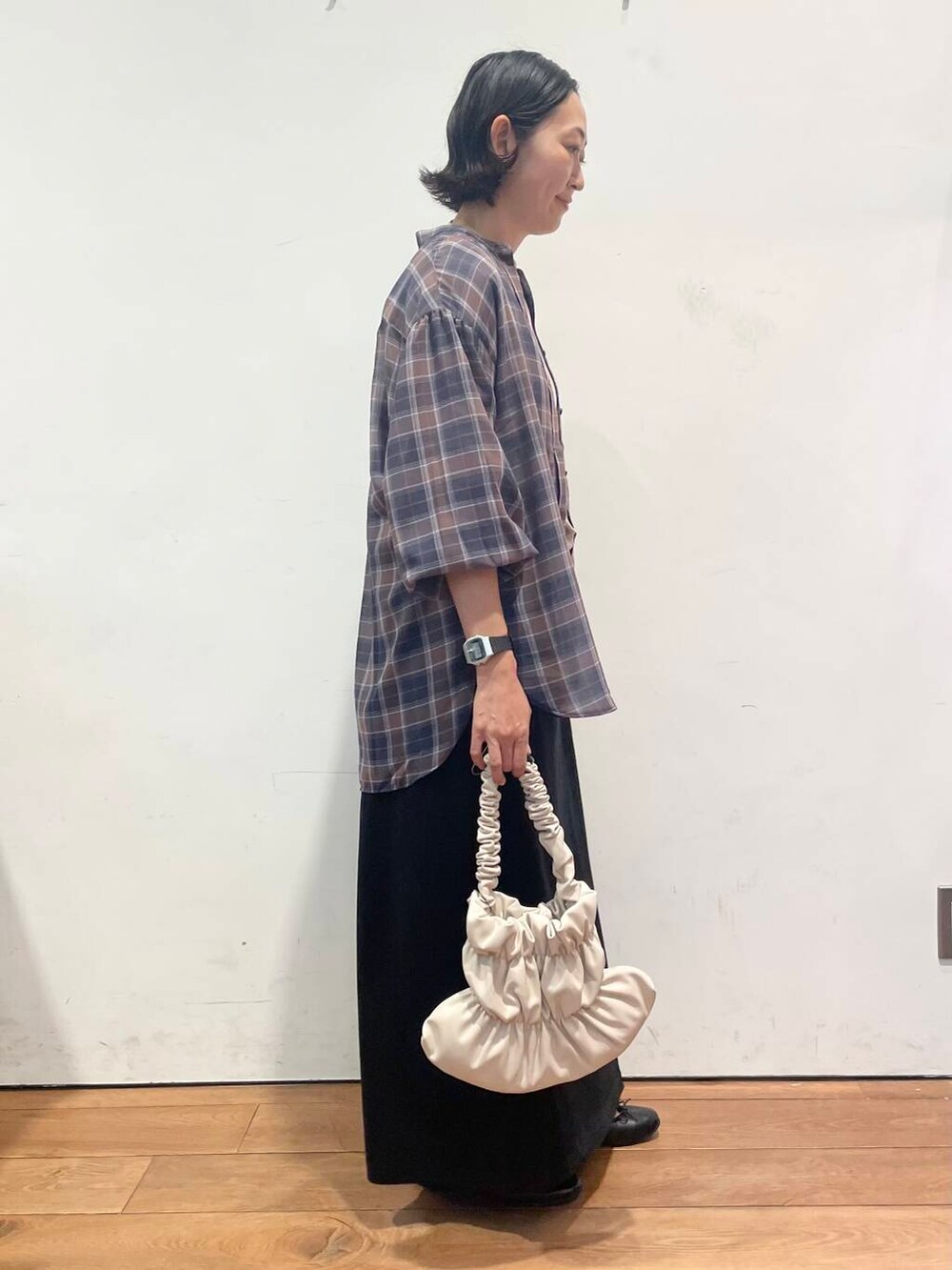 ホワイト系のハンドバッグ、ブラック系のワンピース、ブラック系のスカートを着用したレディースの秋コーディネートの7枚目の写真