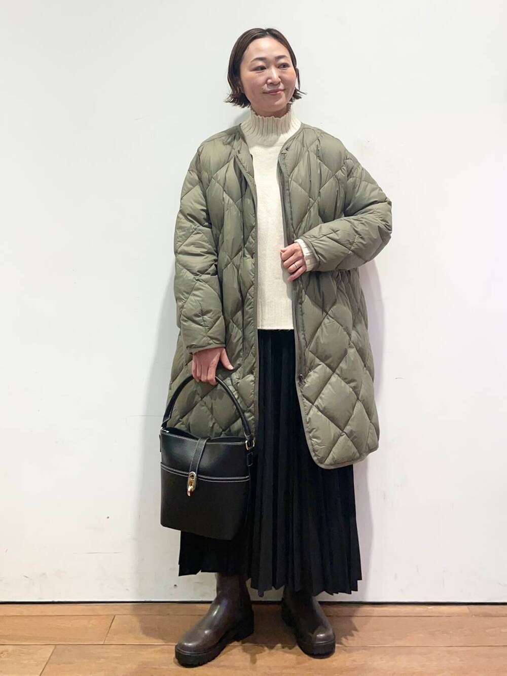 グリーン系のダウンジャケット/コート、ブラック系のハンドバッグ、ブラウン系のブーツを着用したレディースの冬コーディネートの2枚目の写真
