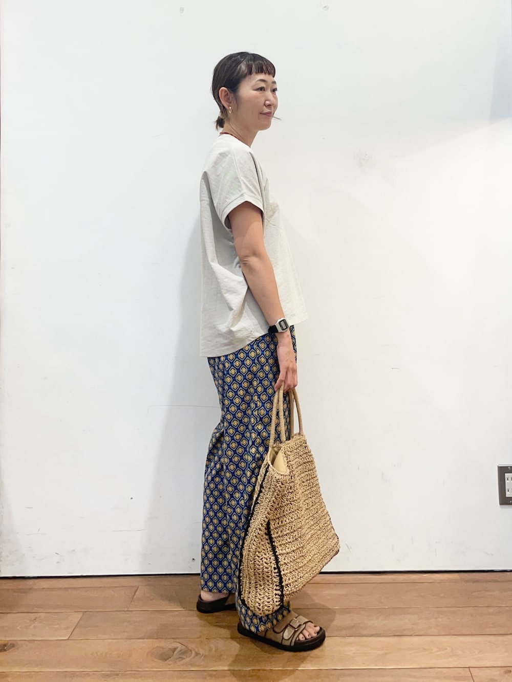グレー系のTシャツ/カットソー、ブルー系のその他パンツ、ベージュ系のトートバッグを着用したレディースの夏コーディネートの3枚目の写真