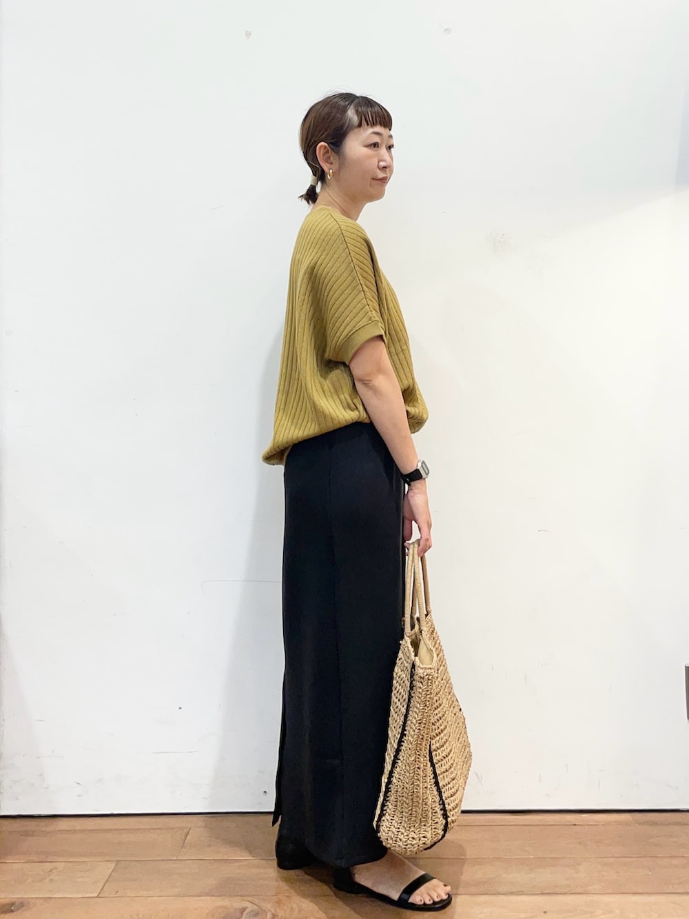 イエロー系のTシャツ/カットソー、ベージュ系のトートバッグ、ブラック系のスカートを着用したレディースの夏コーディネートの4枚目の写真