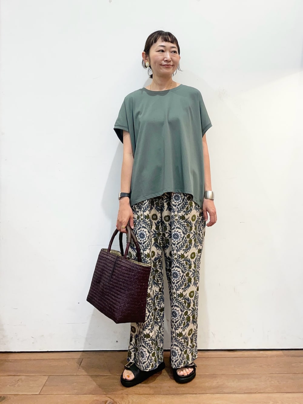 グリーン系のTシャツ/カットソー、ベージュ系のその他パンツ、ブラック系のサンダルを着用したレディースの夏コーディネートの2枚目の写真