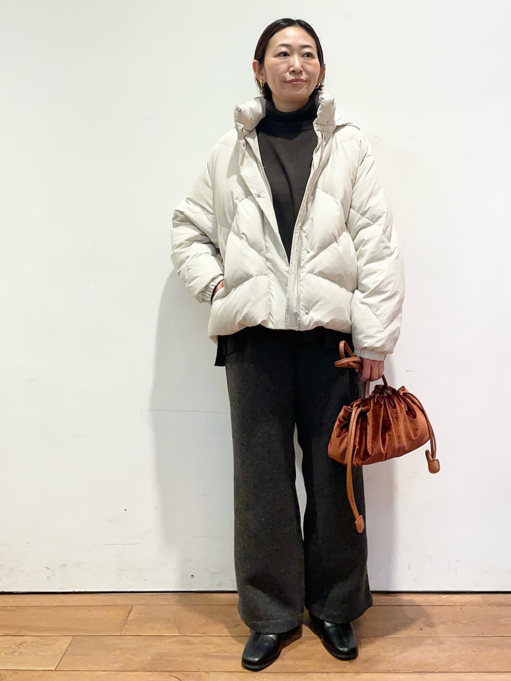 ホワイト系のダウンジャケット/コート、ブラウン系のニット/セーター、ブラック系のブーツを着用したレディースの秋コーディネートの2枚目の写真