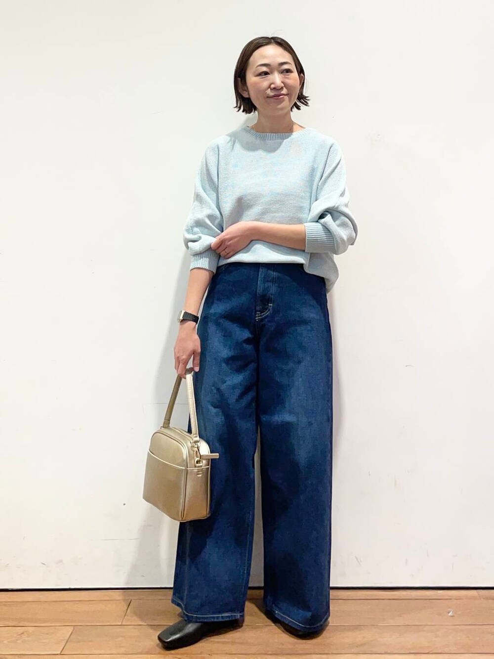 ゴールド系のショルダーバッグ、ブラック系のバレエシューズ、ブルー系のデニムパンツを着用したレディースの冬コーディネートの2枚目の写真