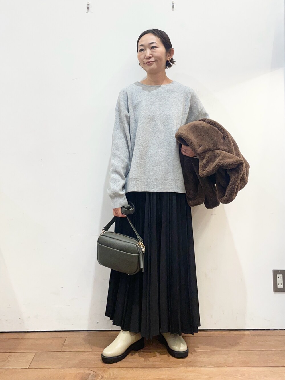 ブラウン系のその他アウター、グレー系のニット/セーター、グリーン系のショルダーバッグを着用したレディースの冬コーディネートの5枚目の写真