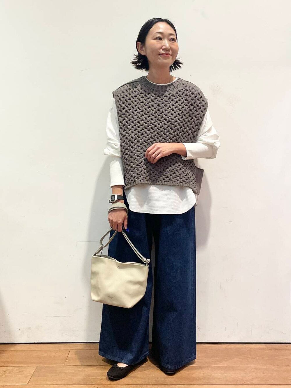 ブラック系のバレエシューズ、ブルー系のデニムパンツ、グレー系のベストを着用したレディースの秋コーディネートの2枚目の写真