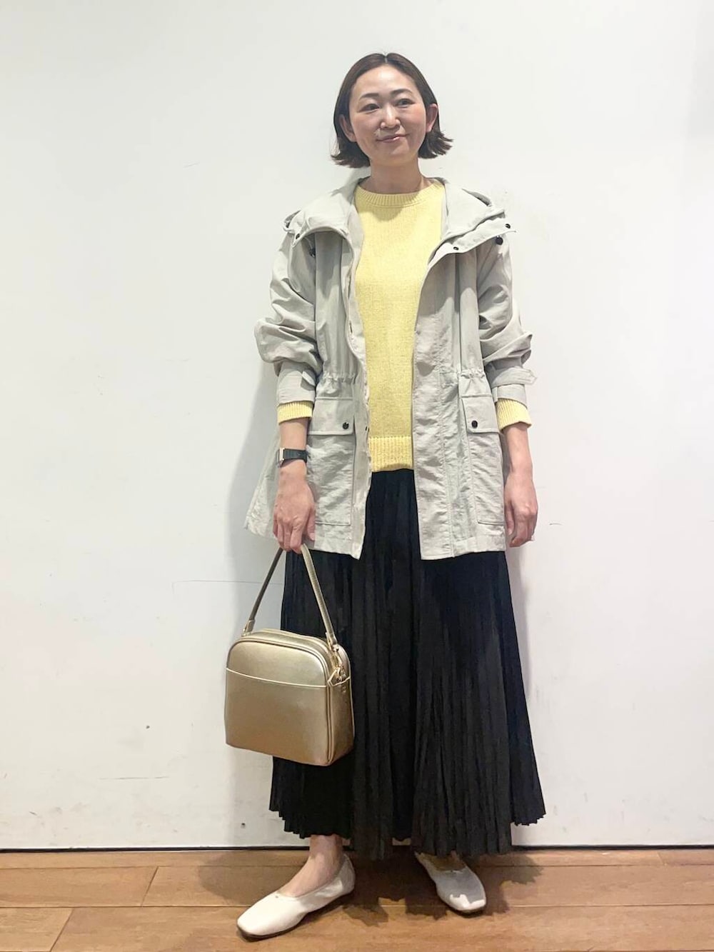 ゴールド系のショルダーバッグ、ブラック系のスカート、ホワイト系のバレエシューズを着用したレディースの春コーディネートの2枚目の写真