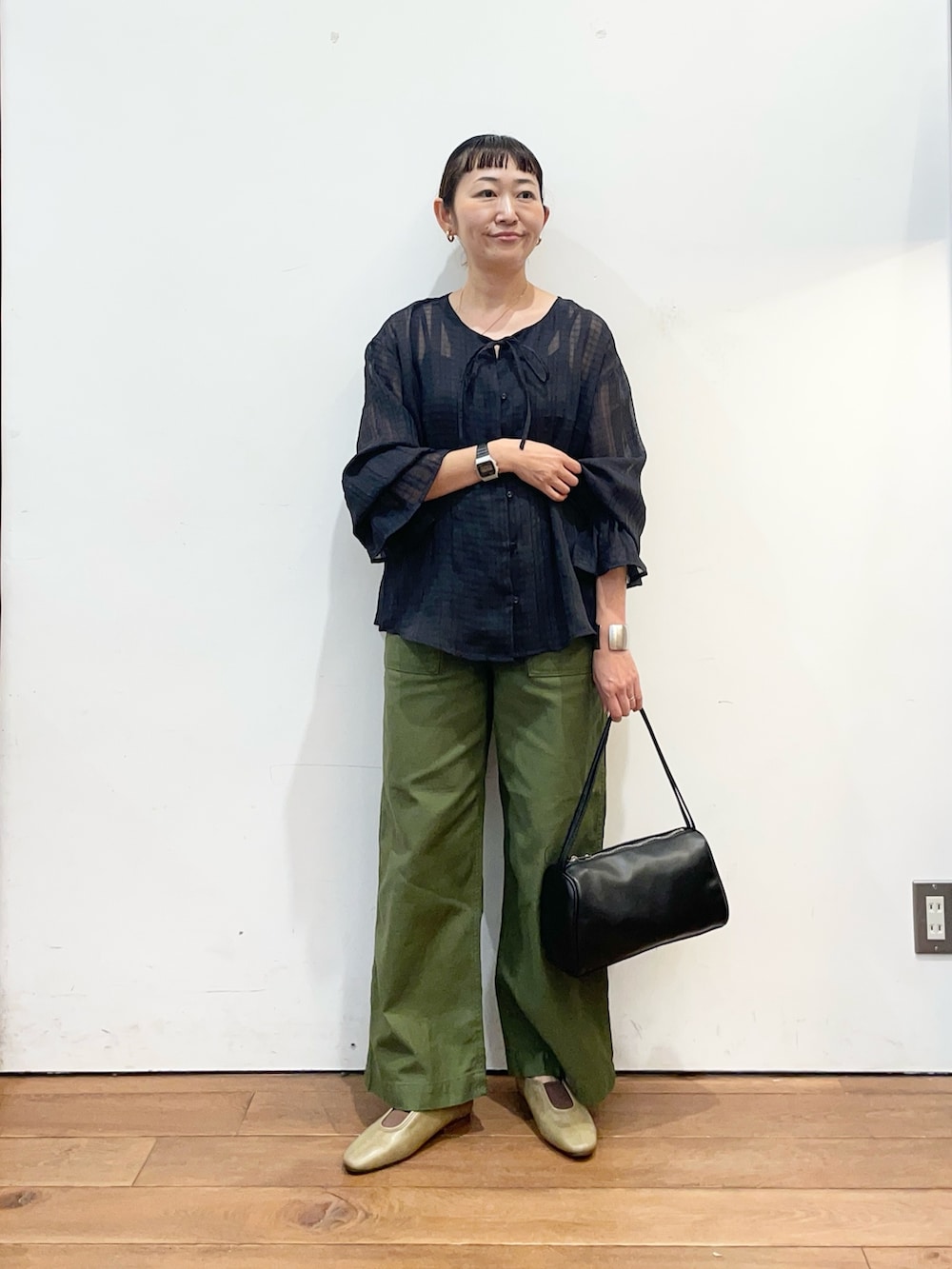 ブラック系のシャツ/ブラウス、グリーン系のその他パンツ、ブラック系のハンドバッグを着用したレディースの秋コーディネートの2枚目の写真