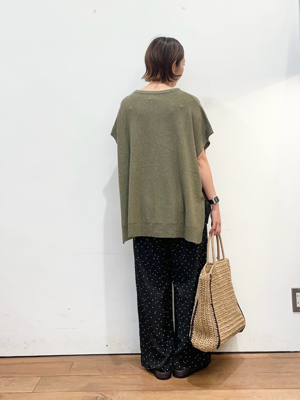 グリーン系のニット/セーター、ブラック系のその他パンツ、ベージュ系のトートバッグを着用したレディースの春コーディネートの4枚目の写真