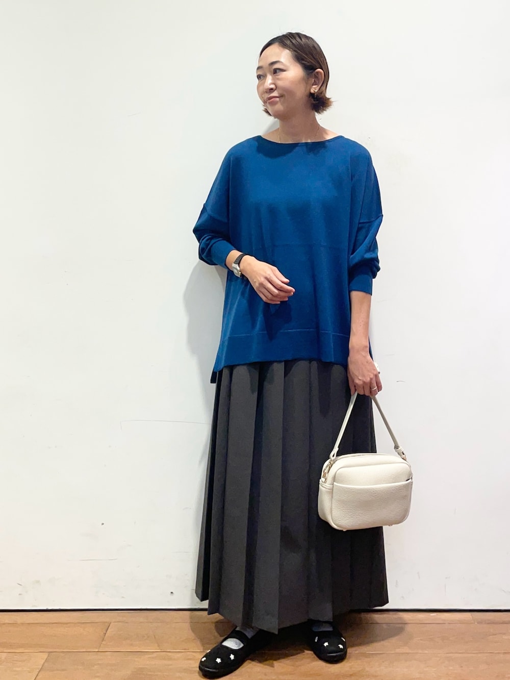 ブルー系のニット/セーター、ブラック系のスニーカー、グレー系のスカートを着用したレディースの秋コーディネートの2枚目の写真