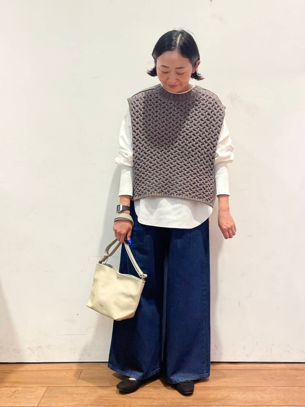 ブラック系のバレエシューズ、ブルー系のデニムパンツ、グレー系のベストを着用したレディースの秋コーディネートの3枚目の写真