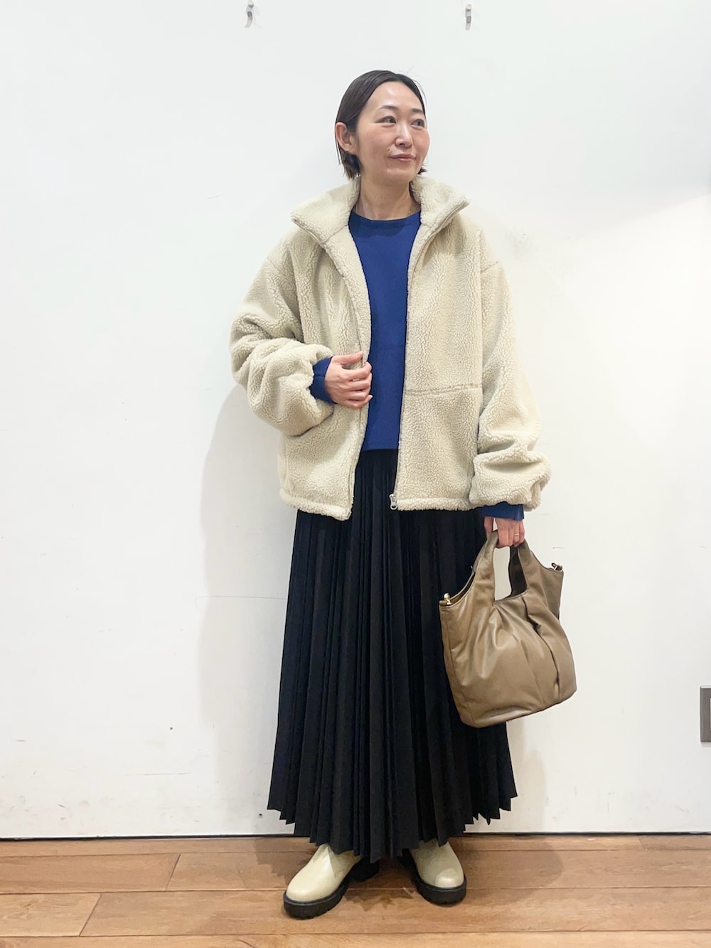 ホワイト系のその他アウター、ブルー系のニット/セーター、ブラック系のスカートを着用したレディースの冬コーディネートの2枚目の写真
