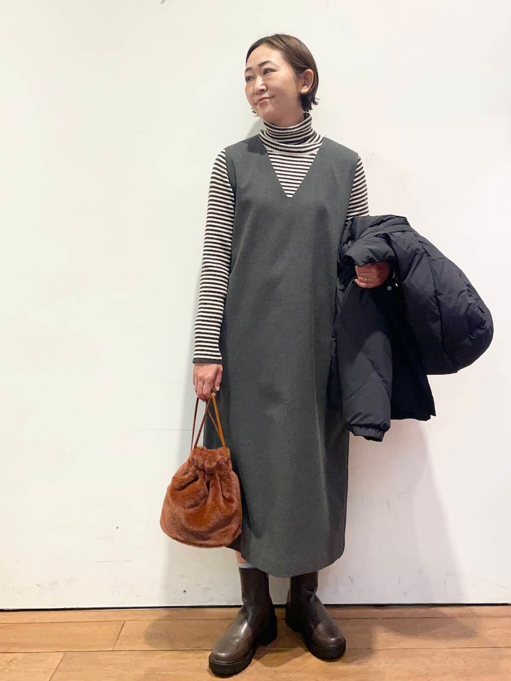 ブラック系のダウンジャケット/コート、グレー系のワンピース、ブラウン系のブーツを着用したレディースの冬コーディネートの5枚目の写真