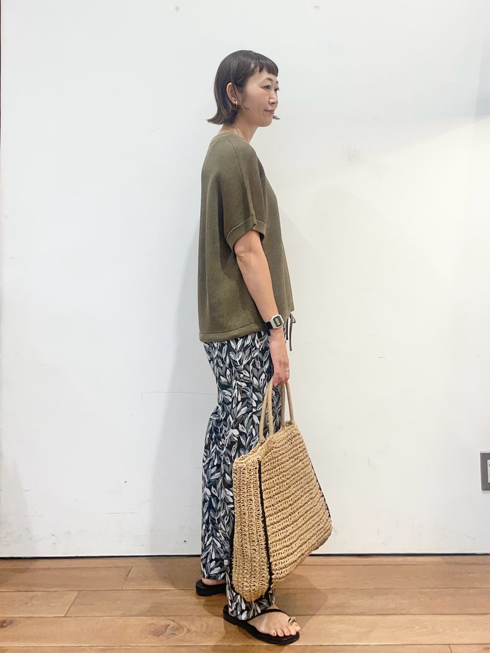 グリーン系のニット/セーター、ブラック系のその他パンツ、ベージュ系のトートバッグを着用したレディースの夏コーディネートの3枚目の写真