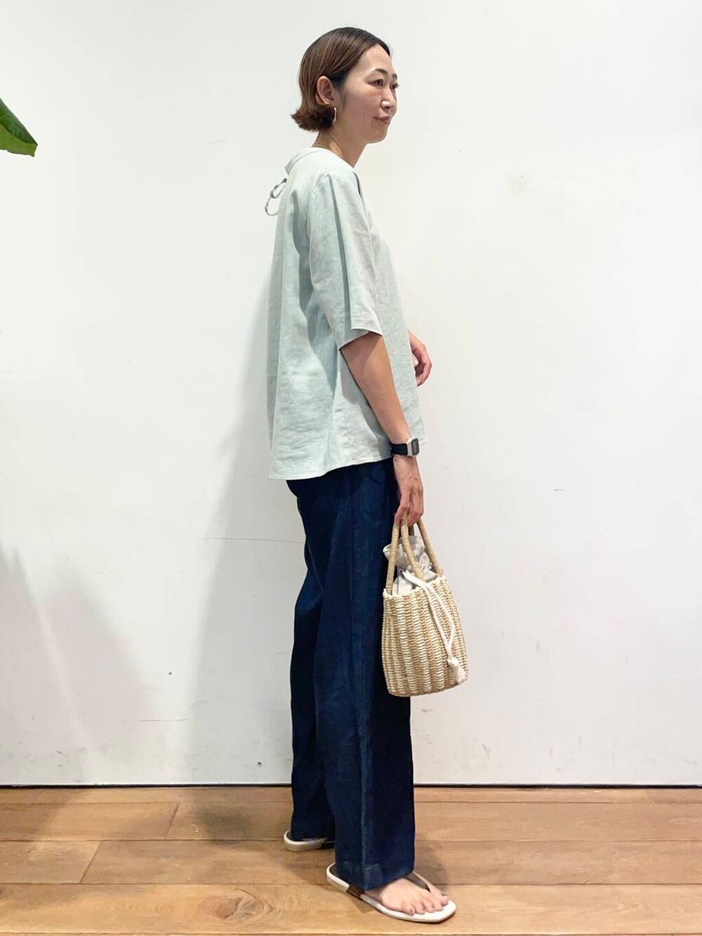 グレー系のハンドバッグ、ブラウン系のサンダル、ブルー系のデニムパンツを着用したレディースの夏コーディネートの4枚目の写真