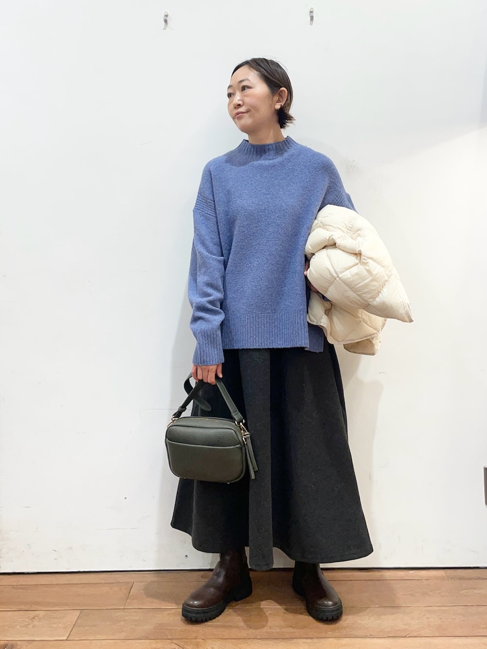 ホワイト系のダウンジャケット/コート、ブルー系のニット/セーター、グリーン系のショルダーバッグを着用したレディースの冬コーディネートの6枚目の写真