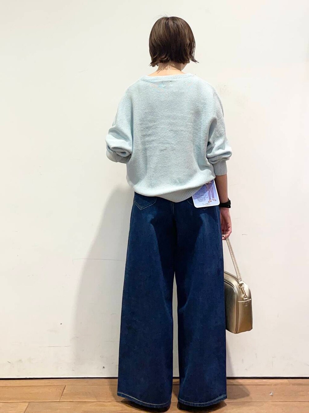 ゴールド系のショルダーバッグ、ブラック系のバレエシューズ、ブルー系のデニムパンツを着用したレディースの冬コーディネートの5枚目の写真