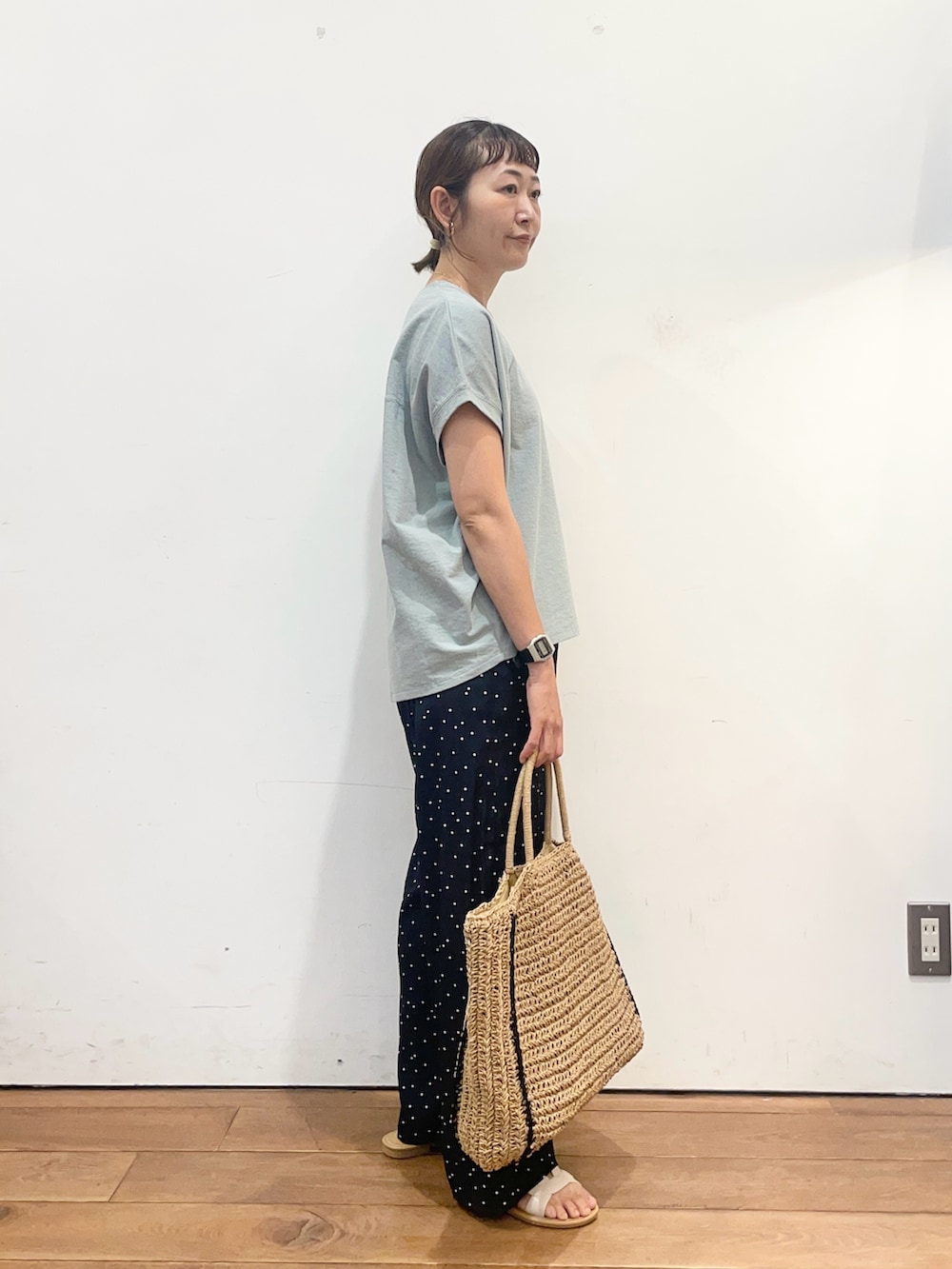 グリーン系のTシャツ/カットソー、ベージュ系のトートバッグ、ホワイト系のサンダルを着用したレディースの夏コーディネートの3枚目の写真