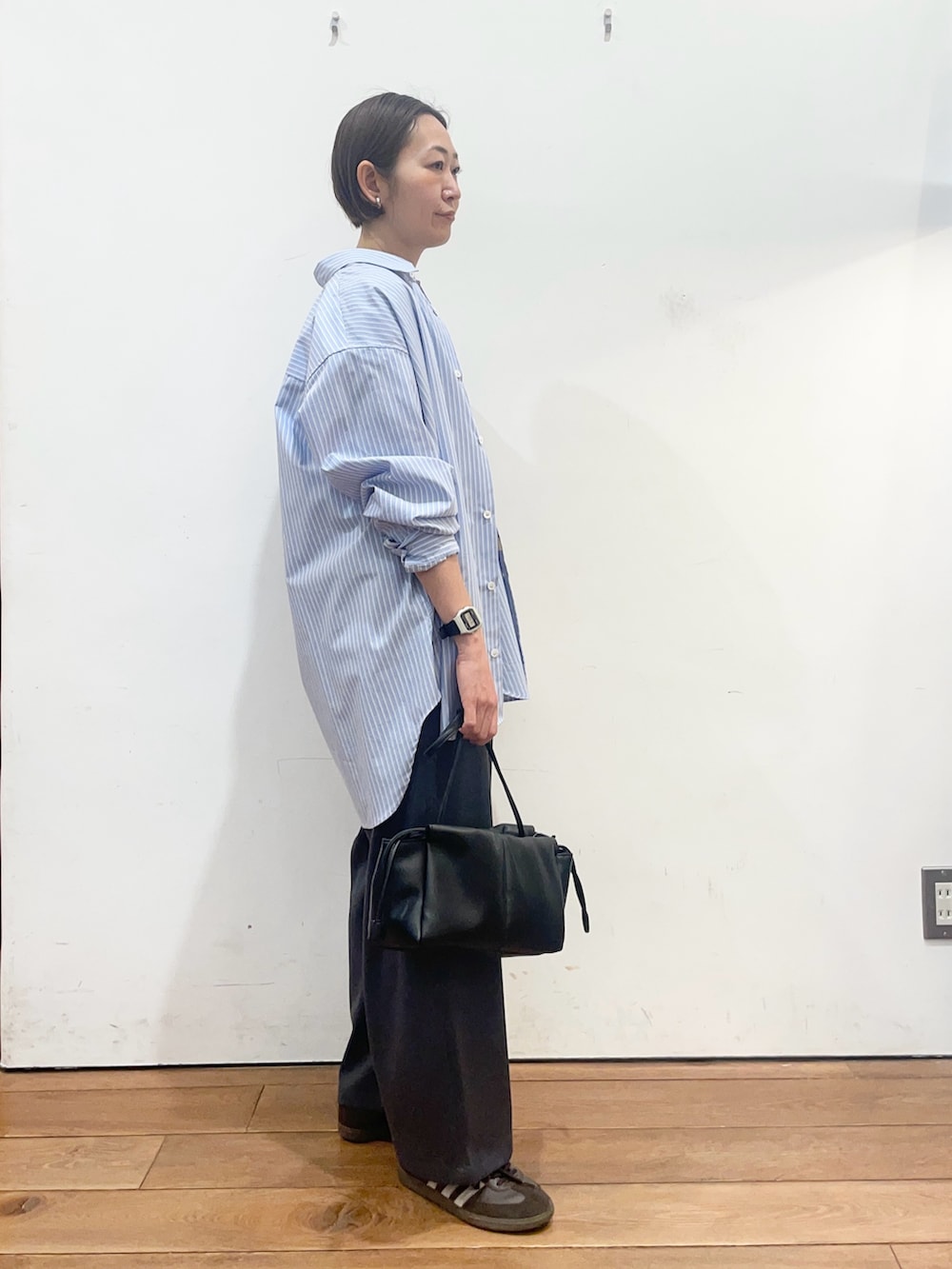 ブラック系のショルダーバッグ、ブルー系のシャツ/ブラウス、ブラウン系のTシャツ/カットソーを着用したレディースの春コーディネートの3枚目の写真