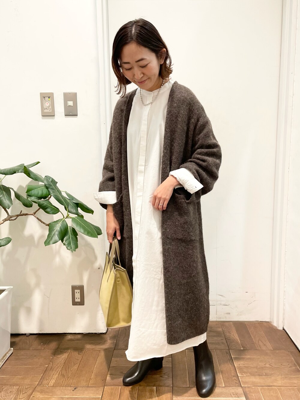 ブラウン系のカーディガン/ボレロ、ホワイト系のワンピース、イエロー系のショルダーバッグを着用したレディースの冬コーディネートの2枚目の写真