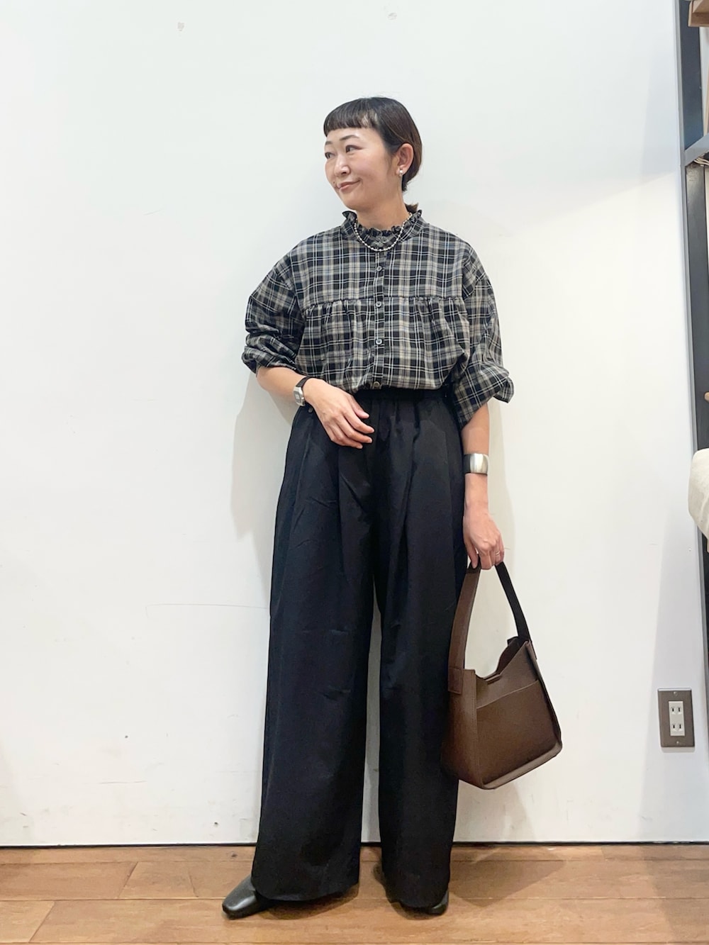ブラック系のシャツ/ブラウス、ブラック系のその他パンツ、ブラウン系のハンドバッグを着用したレディースの秋コーディネートの2枚目の写真